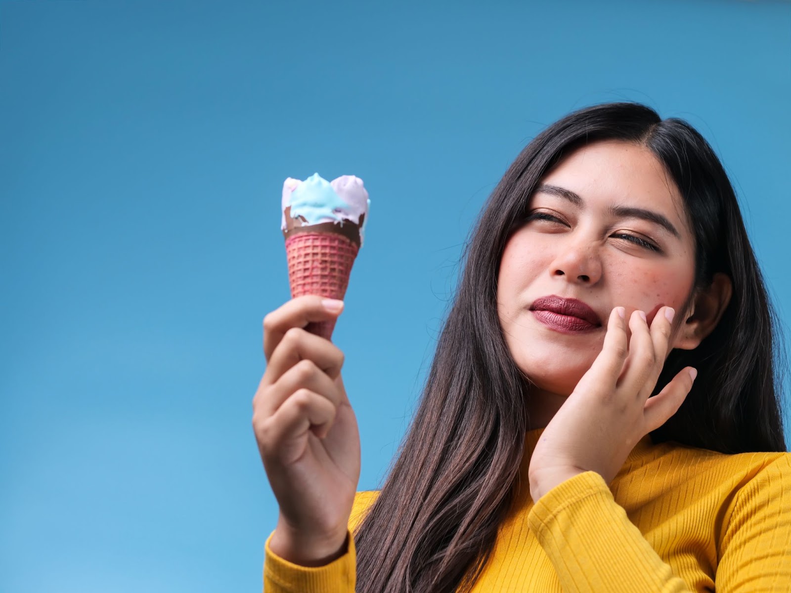 Woman experiencing tooth sensitivity after eating some ice cream