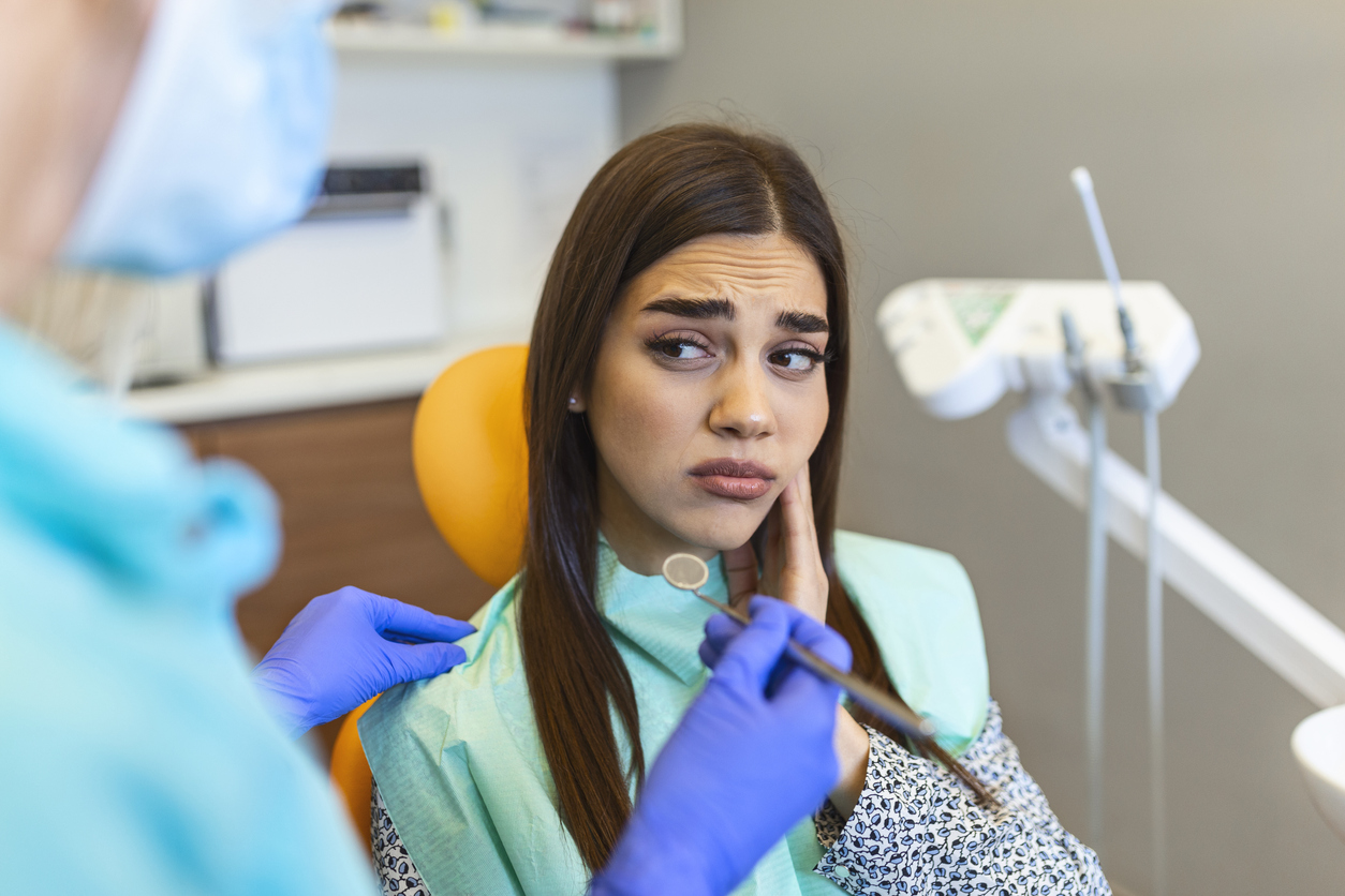 woman sitting in dental chair as dentist prepares to examine her cavity