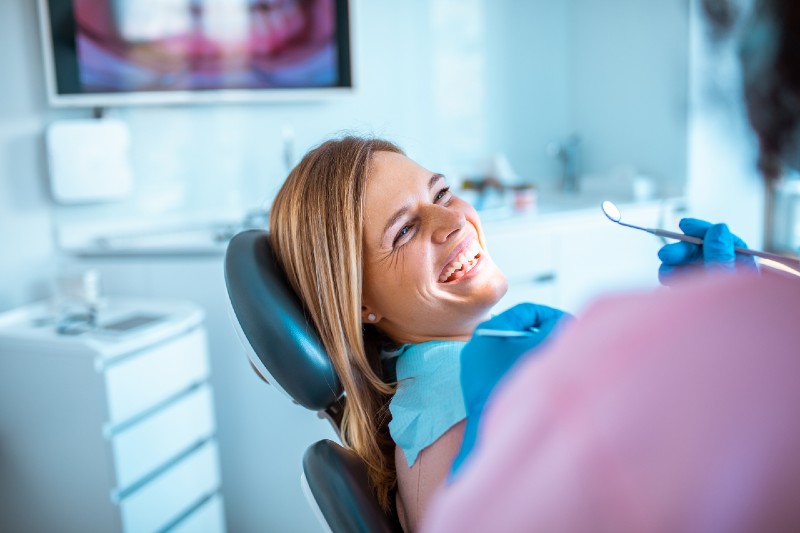Woman sitting in dental chair smiling during regular exam