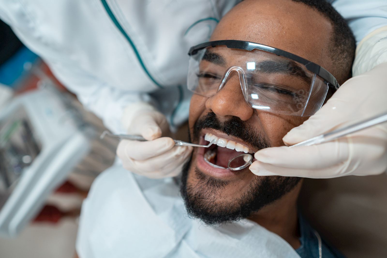 man in dental chair getting tartar cleaned off his teeth