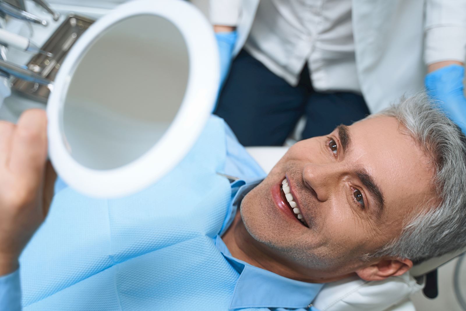 Man admiring dental work in mirror after dentist appointment