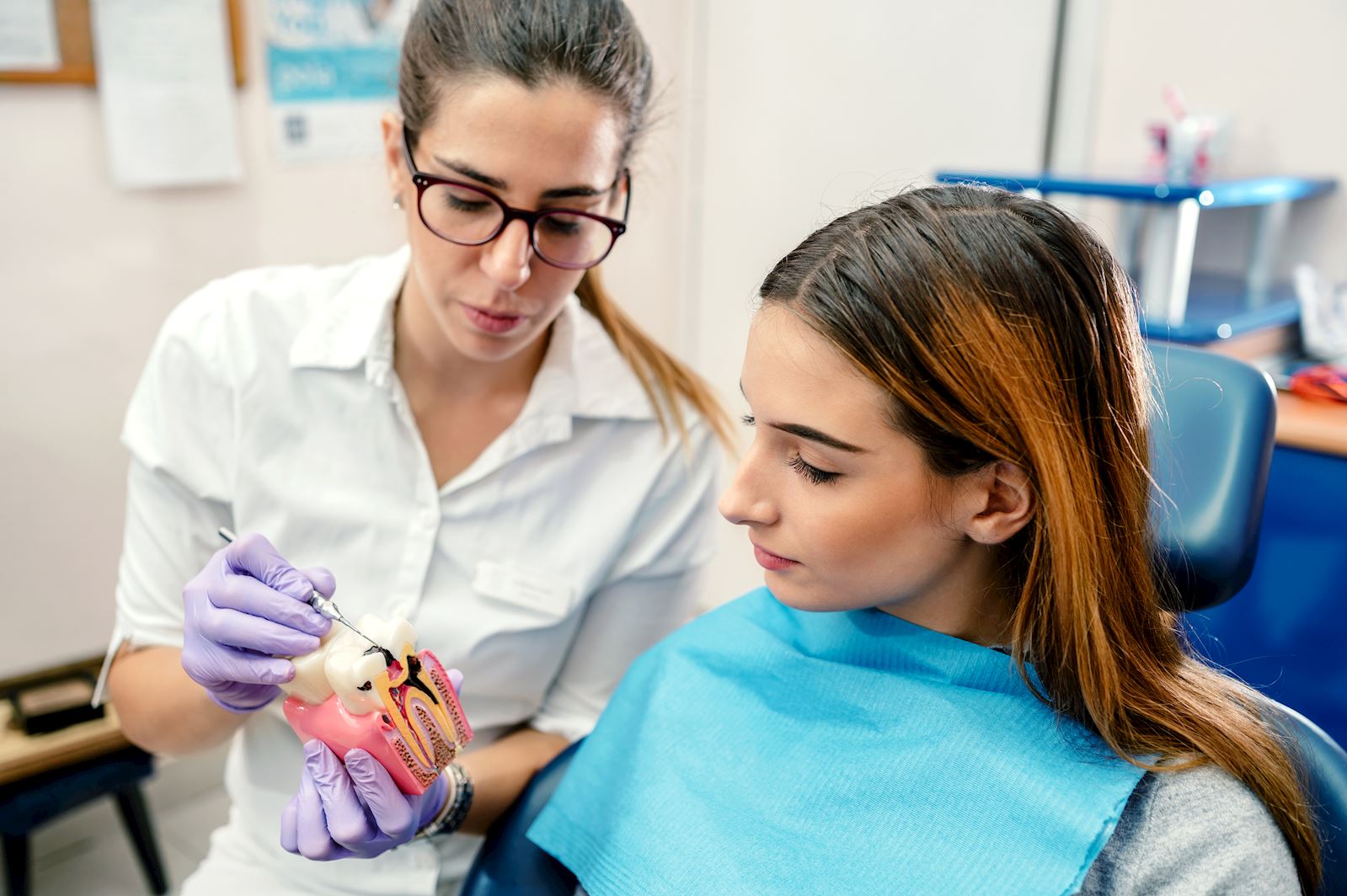dentist demonstrating proper care to patient on model of tooth