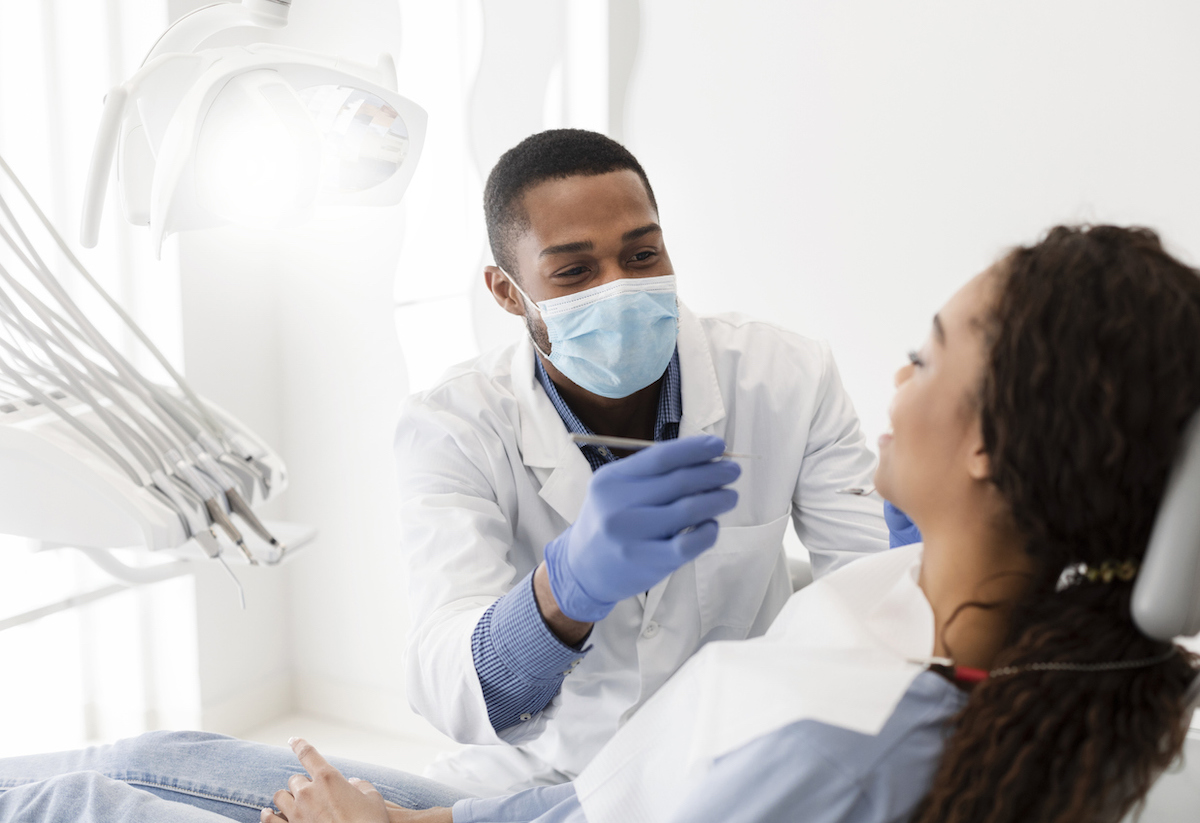 dentist talking to patient while performing cleaning