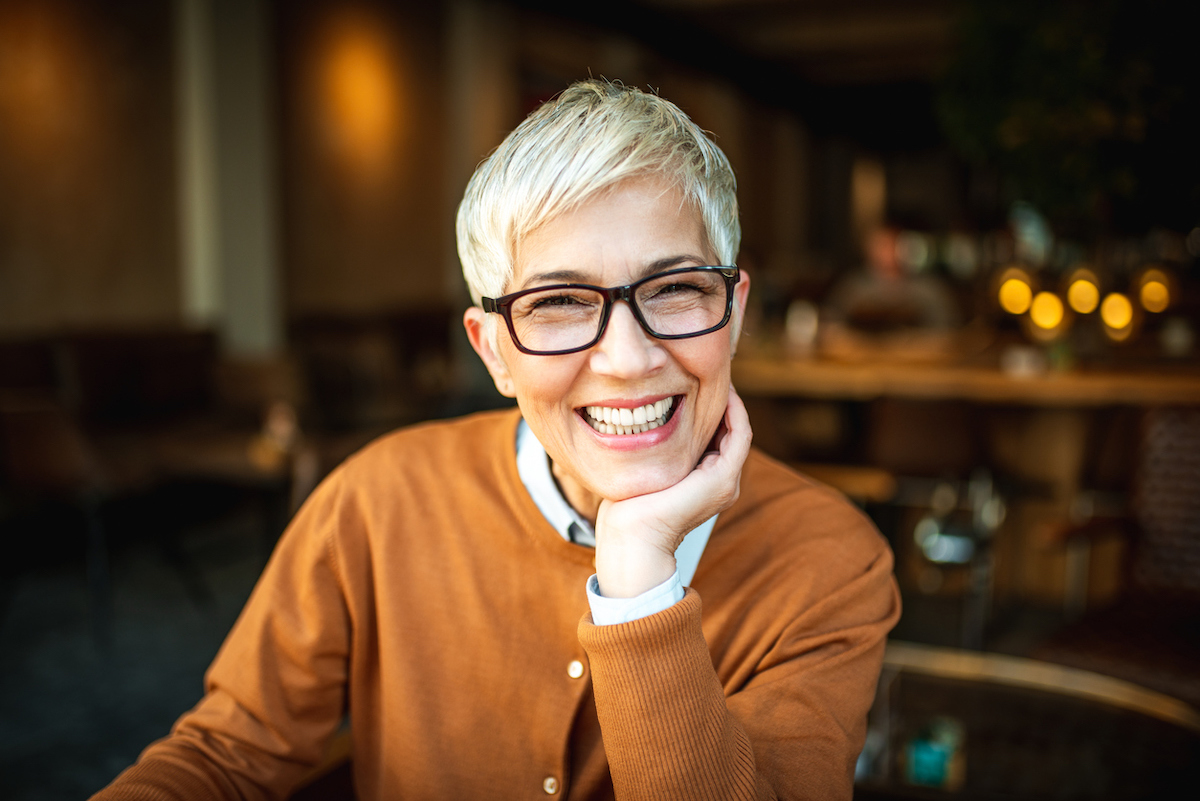 older adult woman sitting at a restaurant and smiling